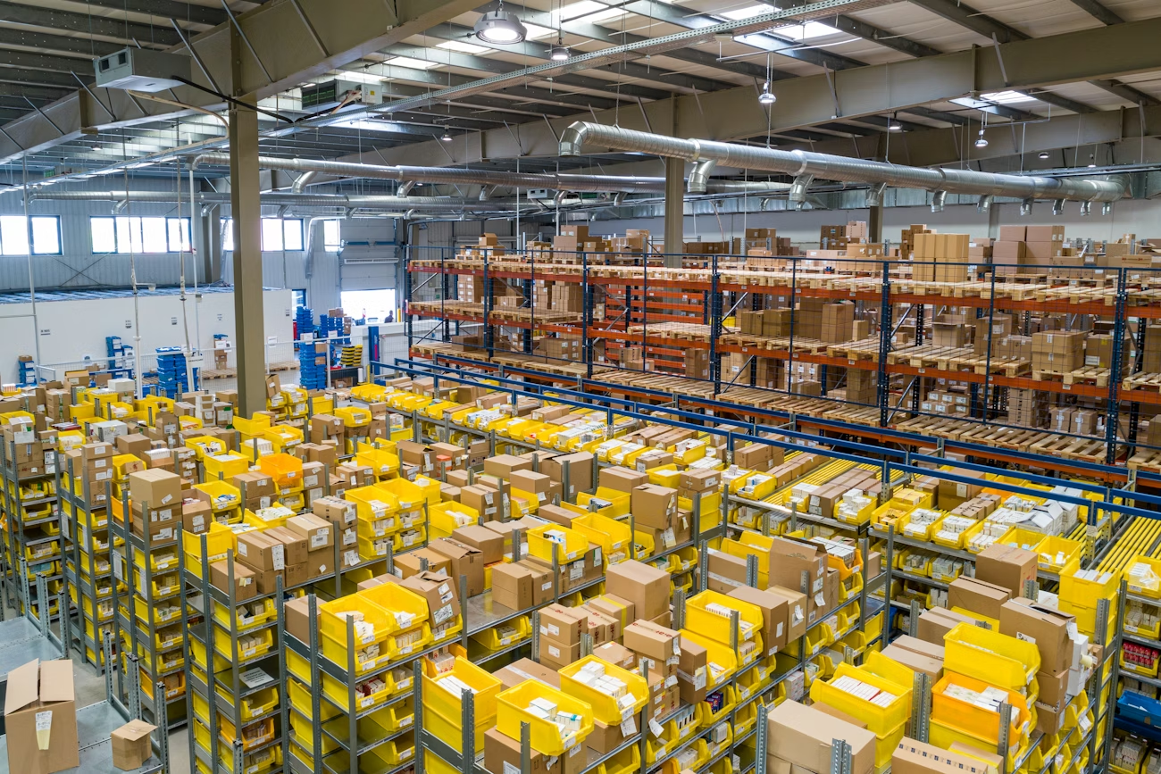 Large warehouse filled with shelves and yellow-packaged boxes under bright lighting.